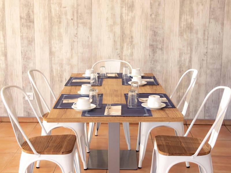 Tavolo da pranzo moderno con sedie in metallo bianco e tazze da caffè in una stanza luminosa