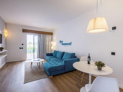 Modern living room with blue sofa, round table, TV, and balcony access.