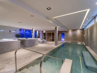 Modern wellness area with hot tub, sauna, and swimming pool in elegant design.