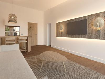 Bright living room with sofa, wall-mounted TV, and small desk with chair.