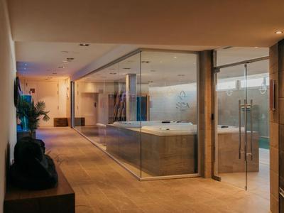 Spa moderno de hotel con jacuzzi y paredes de vidrio.