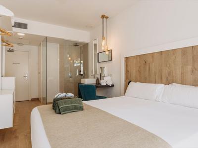 Habitación de hotel moderna con cama doble, detalles de madera y área de trabajo práctica.