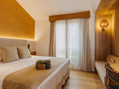 Acogedora habitación de hotel con cama grande, almohadas y luz cálida.