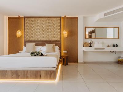 Área de dormitorio de hotel moderna con cama plataforma de madera iluminada y decoración minimalista.