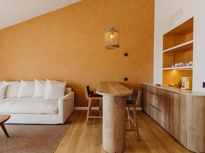 Área de estar moderna con sofá blanco, mesa de madera y estantería abierta en tonos cálidos.