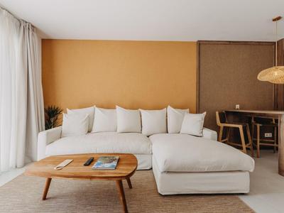 Sala moderna con sofá blanco, mesa de centro de madera y paredes de colores cálidos.