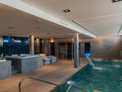 Piscina interior moderna con cascada y áreas de descanso en un hotel.