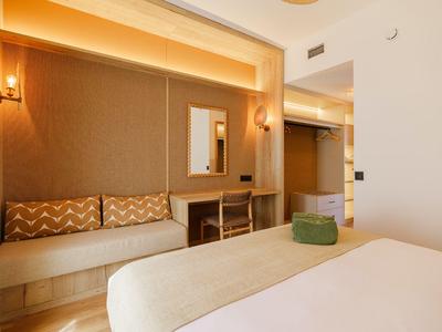 Habitación de hotel moderna con cama, área de estar y escritorio.
