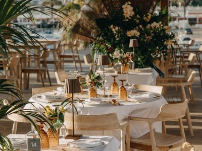 Elegant table with white tablecloth and floral decoration in a restaurant with wooden furniture.