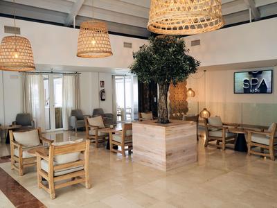 A bright spa waiting area with comfortable chairs and hanging lamps made of natural materials.