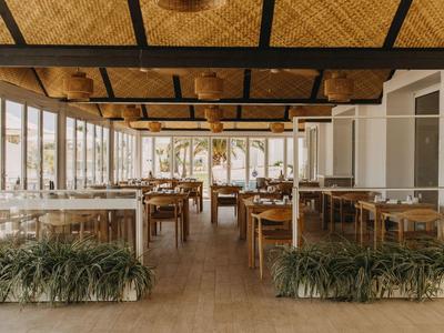 Bright and spacious restaurant with wooden tables and wide views through glass walls.