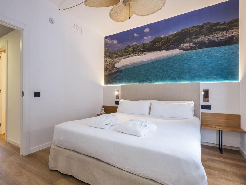 Modern hotel room with large bed, wooden floor, and beach picture above the headboard.