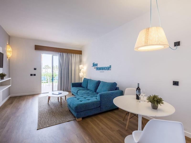 Modern living room with blue sofa, round table, TV, and balcony access.