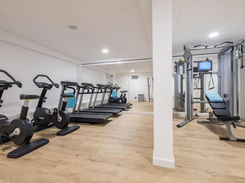 Modern gym with exercise bikes, treadmills, and strength machines in a bright room.