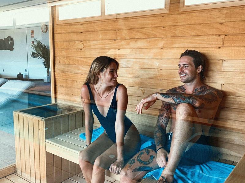 Couple relaxing on a wooden bench in a sauna wellness area.