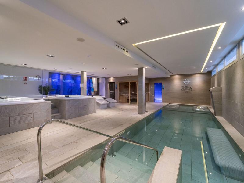 Modern wellness area with hot tub, sauna, and swimming pool in elegant design.