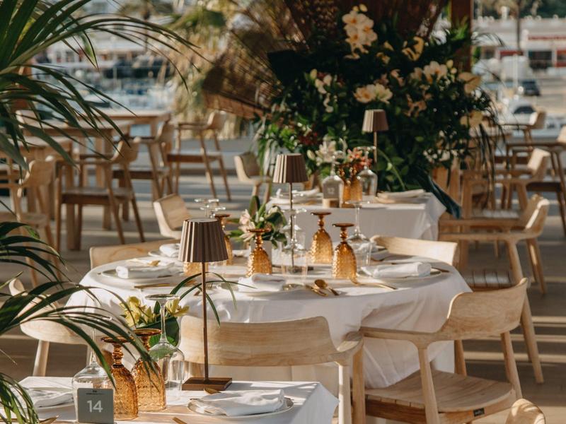 Elegant table with white tablecloth and floral decoration in a restaurant with wooden furniture.