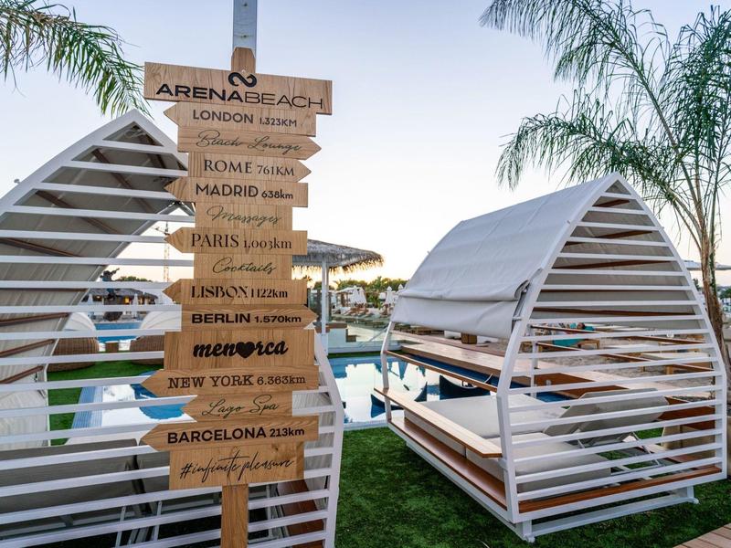 Modern outdoor area with wooden signpost and covered seating at sunset.