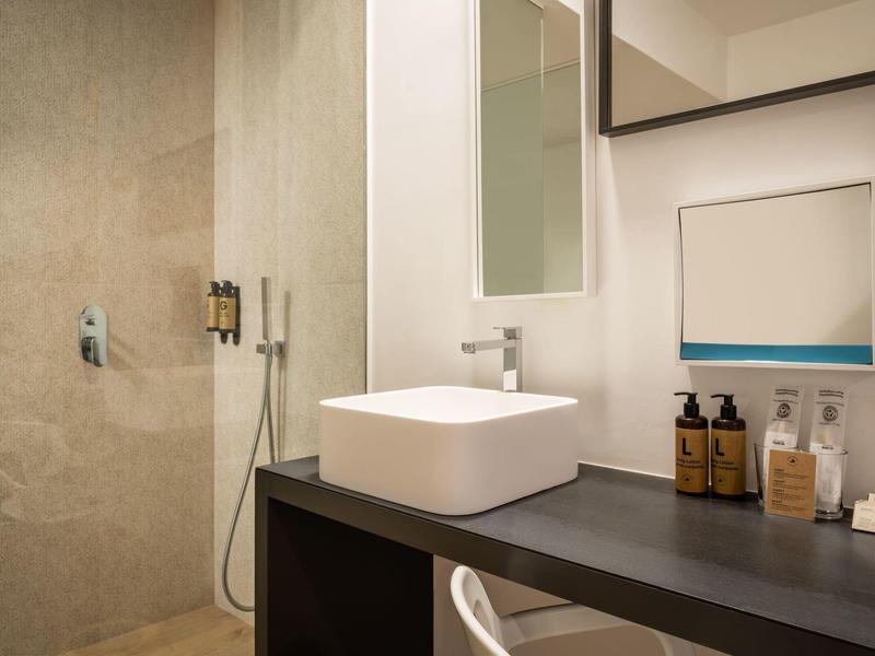 Modern bathroom with sink on dark countertop and walk-in shower.