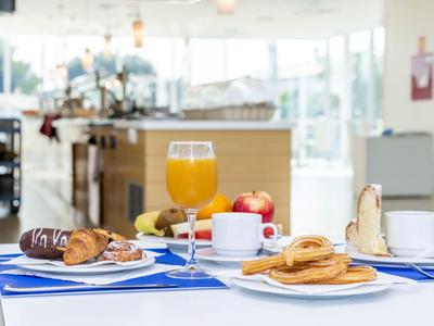Stół śniadaniowy z rogalikami, sokiem, kawą i owocami w jasnej restauracji.