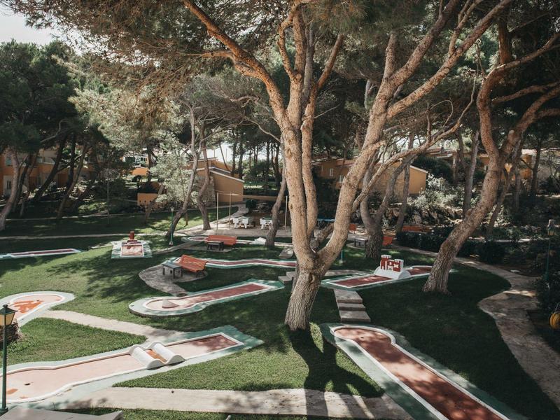 Mini golf course in a wooded area with shaded paths and green playing fields.