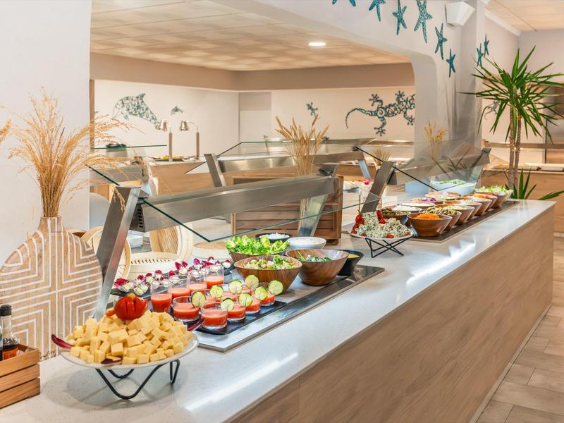 Buffet met desserts en snacks op een houten toonbank in een lichte kamer met planten.