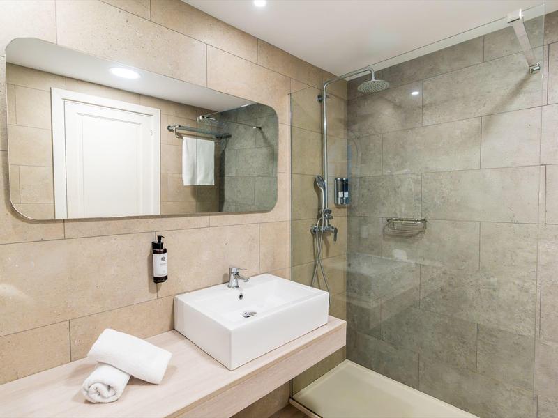 Moderne hotelbadkamer met grote spiegel, wastafel, handdoek en glazen douche.