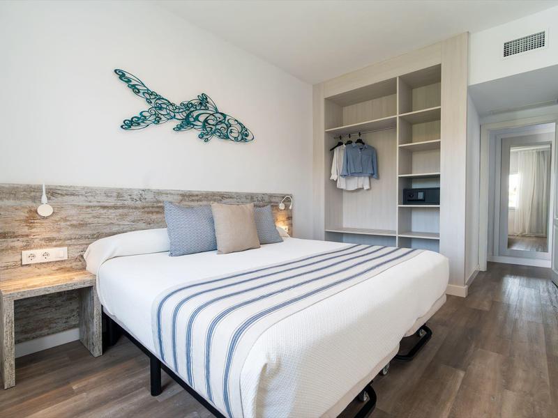 Gezellige hotelkamer met een kingsize bed, houten vloer, vissenwanddecoratie en open kledingkast.