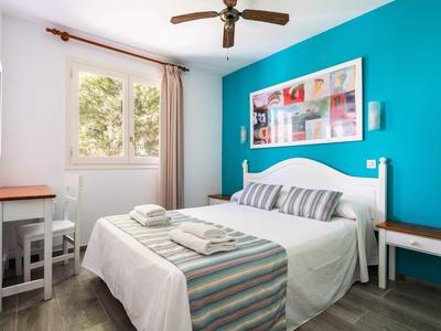 Camera d'hotel accogliente con letto matrimoniale, parete blu e finestra con vista sugli alberi.