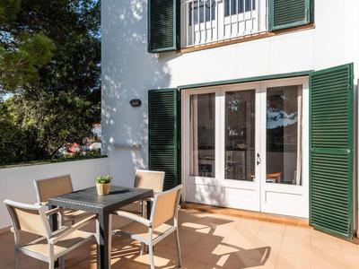 Terrazza con tavolo e sedie davanti a un edificio con pareti bianche e persiane verdi.