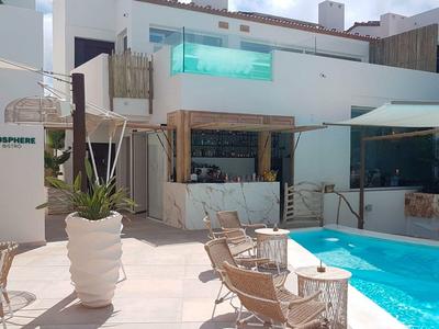 Moderner Hotelpoolbereich mit Liegestühlen, Pflanzen und weißen Gebäuden im Hintergrund.
