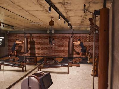 Moderner Fitnessraum mit Holzmöbeln, Sandsäcken und Backsteinwand im Hotel.