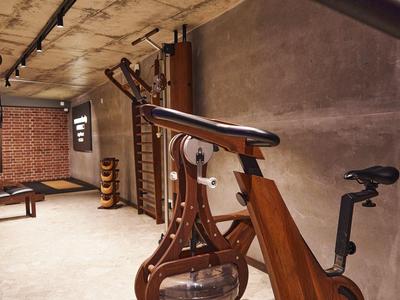 Moderner Fitnessraum mit Holzfahrrad und Gewichten in warm beleuchtetem, rustikalem Raum.