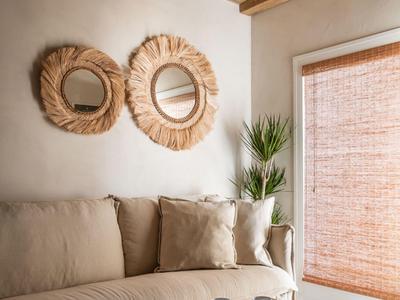 Cozy living room with beige sofa, wooden coffee table, decorative mirrors, and natural light.