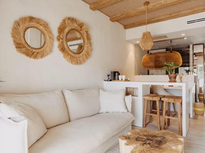 Gemütliches Lounge-Interieur mit weißem Sofa, Holzdekorationen und offenen Küchenbereich.