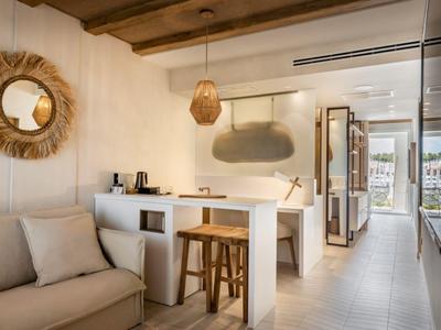 Heller Wohnbereich mit Sofa, Tresen und Naturholzdetails in modernem Hotelzimmer.