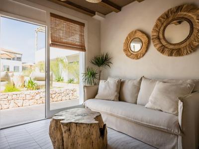 Helles Wohnzimmer mit gemütlichem Sofa, rundem Holzspiegeltisch und Blick auf Garten.