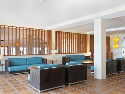 Moderne hotel lobby met blauwe banken, bruine fauteuils en houten scheidingswanden.