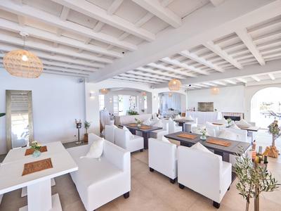 Licht, modern restaurant met witte inrichting en houten balkenplafond.