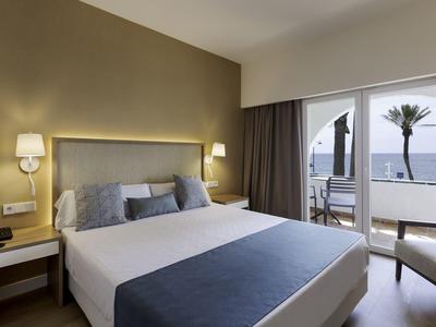 Moderne hotelkamer met groot bed, indirecte verlichting en balkon met zeezicht.