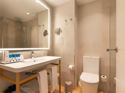 Moderne hotelbadkamer met verlichte spiegel, wastafel en toilet.