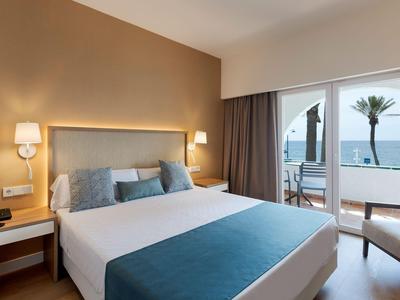 Nowoczesny pokój hotelowy z dużym łóżkiem, balkonem i widokiem na morze.