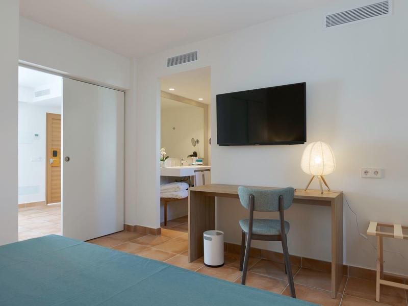 Moderne hotelkamer met bureau, stoel, tv en toegang tot de badkamer.