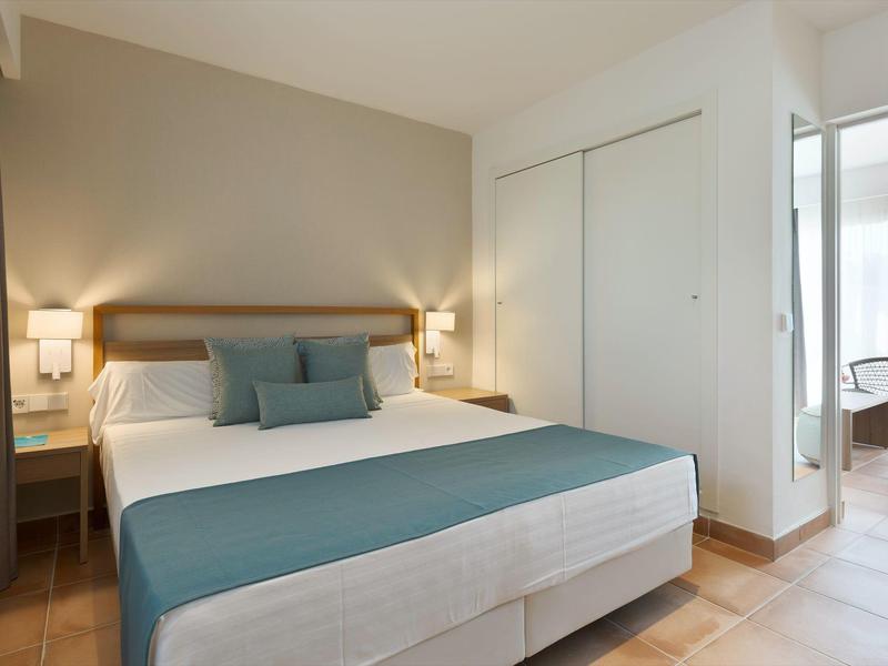 Modern hotelkamer met groot bed, nachtkastjes en eigen balkon.