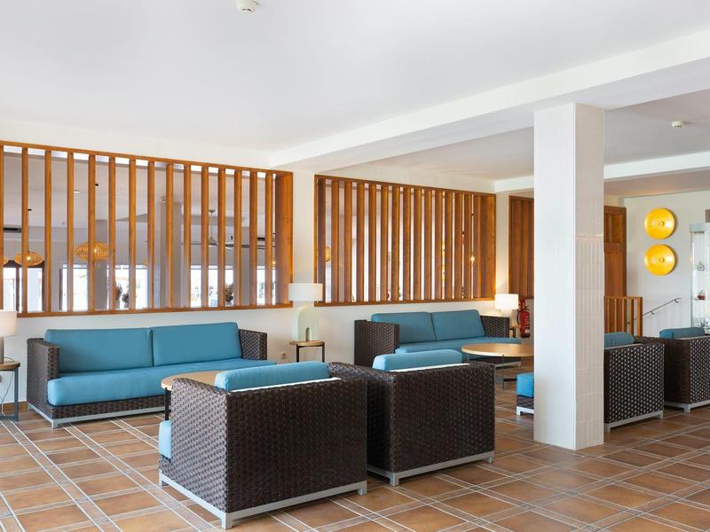 Moderne hotel lobby met blauwe banken, bruine fauteuils en houten scheidingswanden.