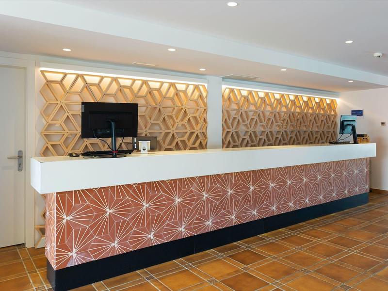 Moderne hotelreceptie met artistieke houten bekleding en betegelde vloer.
