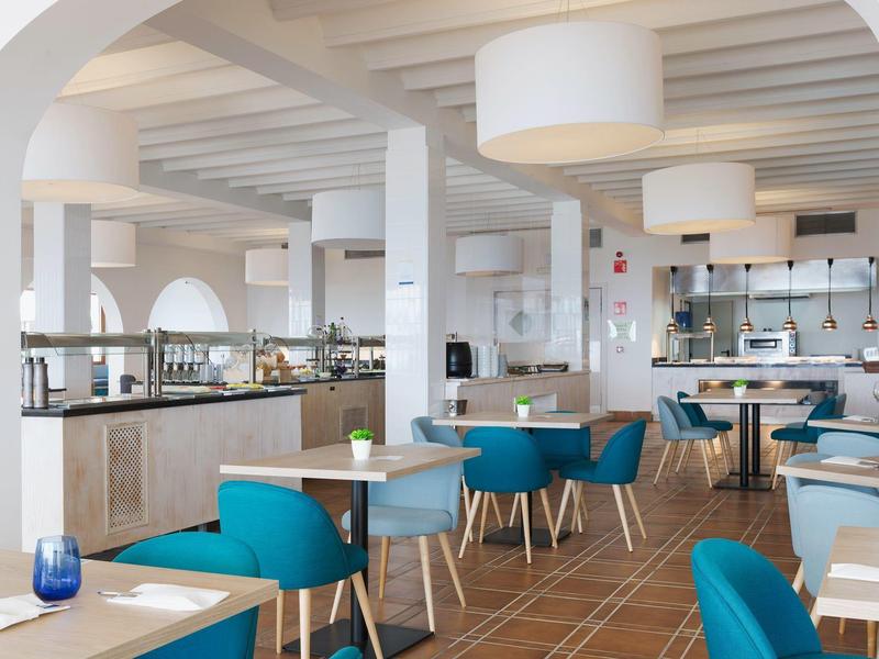 Lichte hotelkeuken met blauw gestoffeerde stoelen en moderne inrichting.