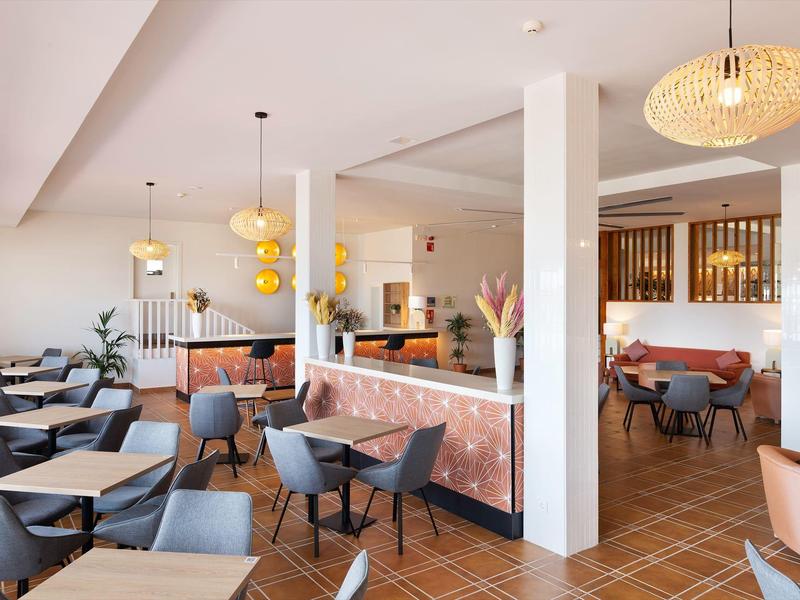 Lichte, modern ingerichte ontbijtruimte met fauteuils en hanglampen in warme kleuren.