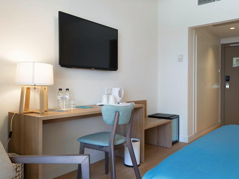 Moderne hotelkamerbureau met tv, flessen water en een comfortabele stoel.