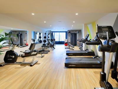 Nowoczesna siłownia z bieżniami, hantlami i dużymi oknami z widokiem na zewnątrz.